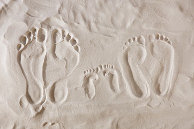 Family footprints on sandy beach, top view