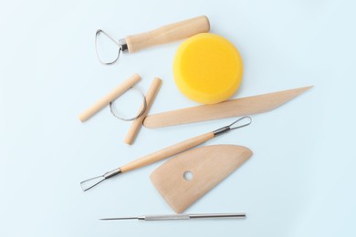 Photo of Set of clay modeling tools on light blue background, flat lay