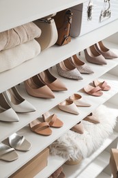 Stylish women's shoes, clothes and bags on shelving unit