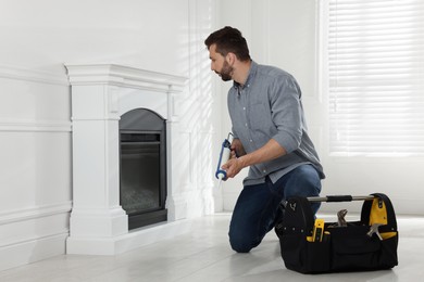 Man installing electric fireplace near white wall in room