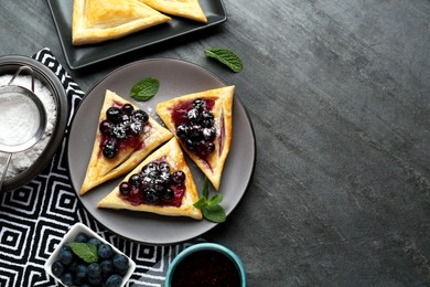 Photo of Fresh tasty puff pastry with sugar powder, jam, sweet berries and mint served on grey table, flat lay. Space for text