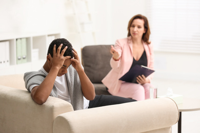 Psychotherapist working with teenage African-American boy in office