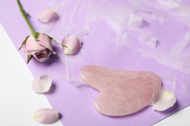Photo of Rose quartz gua sha tool, facial mask and flower on white table