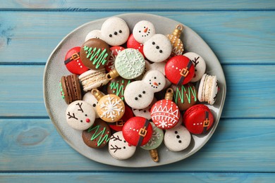 Photo of Beautifully decorated Christmas macarons on light blue wooden table, top view