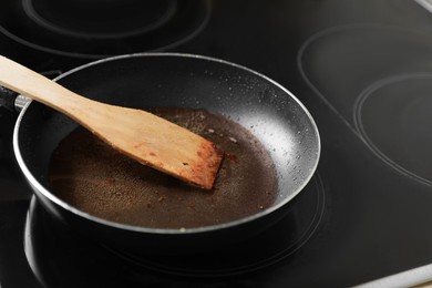 Frying pan with spatula and used cooking oil on stove