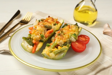 Baked stuffed zucchinis served on white wooden table, closeup