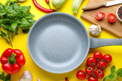Flat lay composition with frying pan and fresh products on yellow background