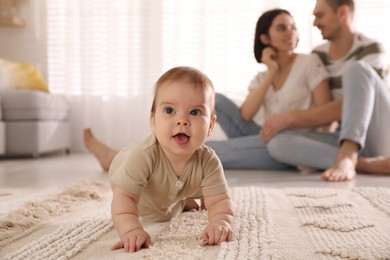Photo of Happy parents watching their cute baby crawl on floor at home