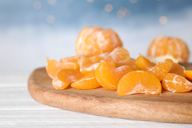 Photo of Segments of fresh juicy tangerines on white wooden table, closeup