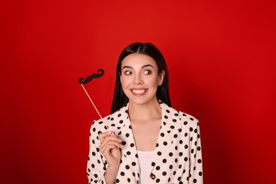 Photo of Emotional woman with fake mustache on red background