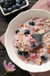 Photo of Tasty oatmeal porridge with toppings on wooden table, flat lay