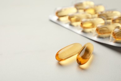 Dietary supplement capsules on white table, closeup. Space for text