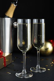 Happy New Year! Glasses with sparkling wine on table against black background
