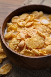 Tasty cornflakes with milk in bowl on wooden table, closeup