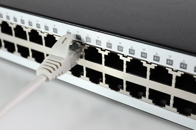 Photo of Closeup view of network switch with cable on light background. Internet connection