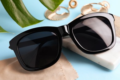 Photo of New stylish elegant sunglasses on turquoise background, closeup