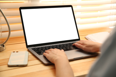 Woman working with modern laptop at wooden table, closeup. Space for design