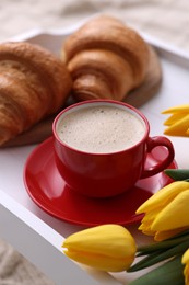 Morning coffee, flowers and croissants on white wooden tray
