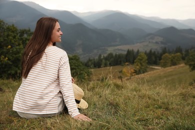 Young woman enjoying beautiful mountain landscape. Space for text