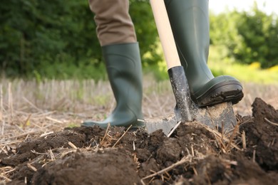 Worker digging soil with shovel outdoors, closeup