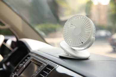 Portable fan on dashboard in car. Summer heat