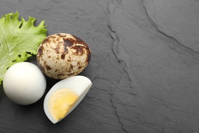 Photo of Unpeeled and peeled hard boiled quail eggs with lettuce leaf on black table, flat lay. Space for text