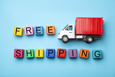 Toy truck with words FREE DELIVERY on blue background, flat lay. Logistics and wholesale concept