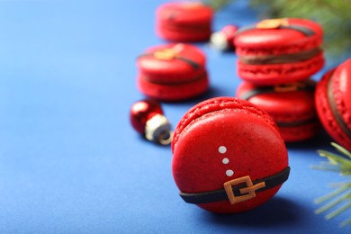 Photo of Beautifully decorated Christmas macarons on blue background, space for text