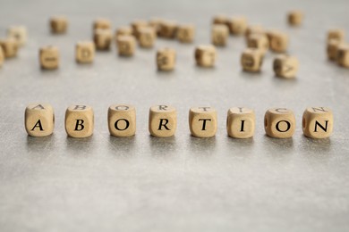 Word Abortion made of wooden cubes on grey table, closeup