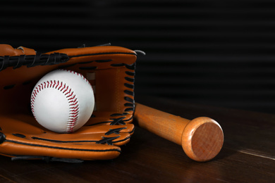 Leather baseball ball, bat and glove on wooden table