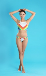 Full length portrait of attractive young woman with slim body in swimwear on color background