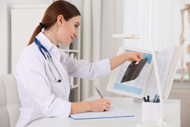 Orthopedist examining X-ray picture at desk in clinic