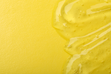 Pure transparent cosmetic gel on yellow background, top view