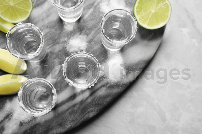 Mexican Tequila shots, lime slices and salt on grey marble table, top view