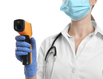 Doctor in latex gloves holding non contact infrared thermometer on white background, closeup. Measuring temperature