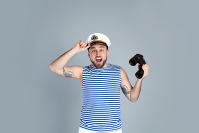 Emotional sailor with binoculars on light grey background