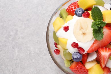 Delicious fruit salad on light grey table, top view. Space for text
