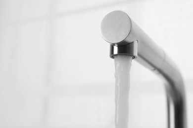 Stream of water flowing from tap on white background, closeup. Space for text