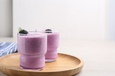 Photo of Delicious blackberry smoothie in glasses on white wooden table. Space for text