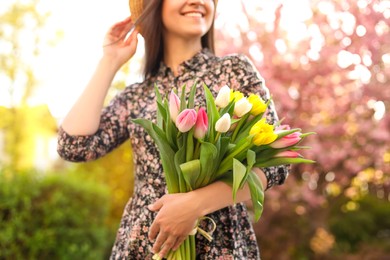 Young woman with bouquet of tulips in park on sunny day, closeup