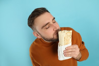 Photo of Young man with delicious shawarma on turquoise background