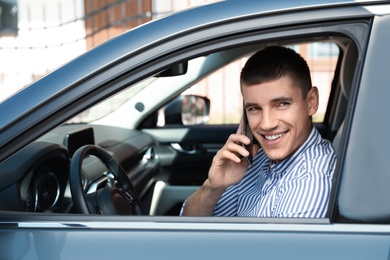Attractive young man talking on phone in luxury car