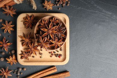 Photo of Flat lay composition with aromatic anise stars and spices on black table, flat lay. Space for text