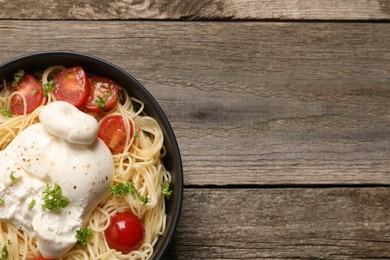 Delicious spaghetti with burrata cheese and tomatoes on wooden table, top view. Space for text