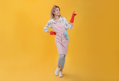 Young housewife in gloves on yellow background