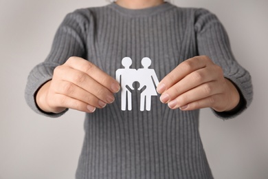 Woman holding paper silhouette of family on grey background, closeup. Life insurance concept