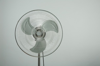 Electric fan on light grey background, space for text. Summer heat
