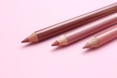 Lip pencils on pink background, closeup. Cosmetic product