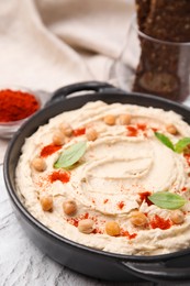 Delicious hummus with chickpeas and paprika served on white textured table, closeup