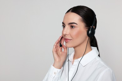 Photo of Hotline operator with modern headset on light grey background, space for text. Customer support